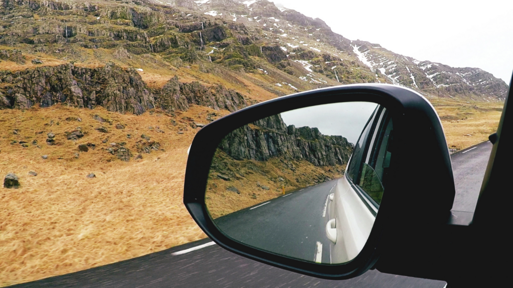 View of a mountain and a quiet Icelandic road from the wing mirror of a car